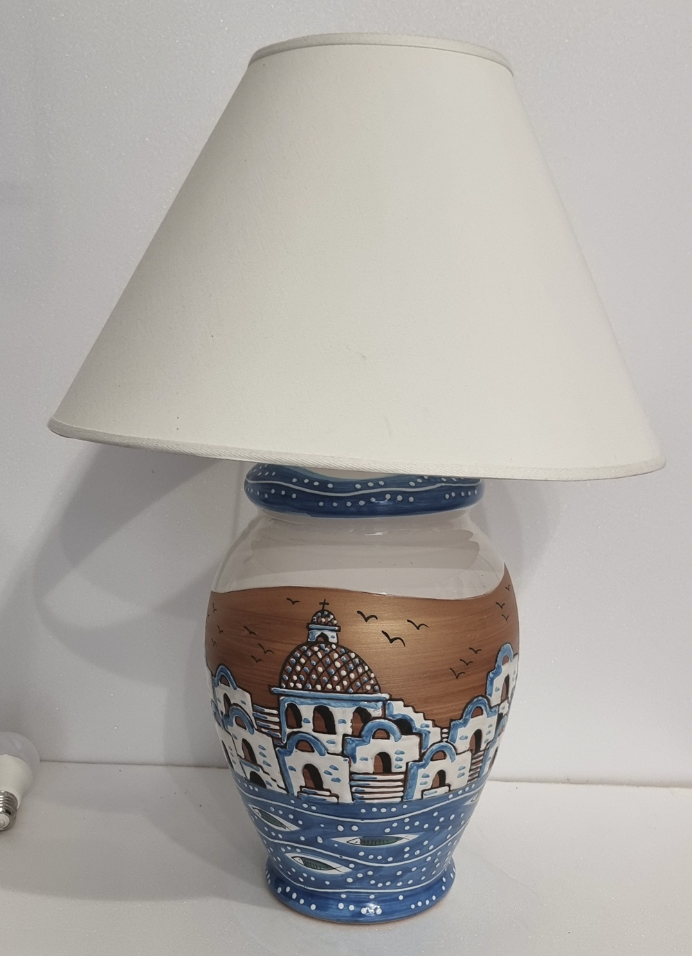 lampada con paralume decorato con casette costiera amalfitana con fondo marino, sormontata in bronzo e bianco